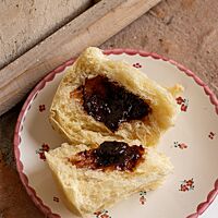 Ein auseinandergezupfter Germknödel zeigt im Inneren die fruchtige Pflaumenfüllung.