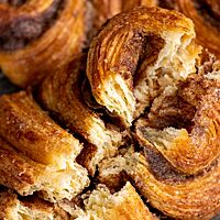 Ein auseinandergebrochenes Franzbrötchen zeigt die feine Blätterung der lockeren Krume.