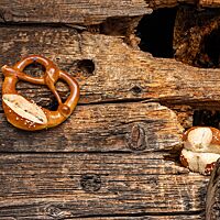 Die Laugenbrezel mit eingeschnittenem Brezelbauch und das kreuzförmig eingeschnittene Laugenbrötchen haben eine glänzende, mit Brezelsalz bestreute Oberfläche.