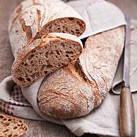 Im Anschnitt zeigt das lange Weizenvollkornbrot die mittelporige, lockere Krume unter der kräftig ausgebackenen, rustikalen Kruste.