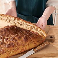 Im Anschnitt der Monster-Focaccia ist die grobporige, lockere Krume zu sehen, die von einer goldbraun ausgebackenen Kruste umgeben ist.