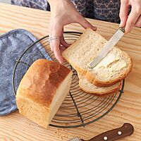 Eine Scheibe des goldbraun ausgebackenen Sandwichbrotes mit heller, fluffiger Krume wird mit Butter bestrichen.