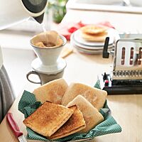 Drei flache, goldgelb ausbackene Toasties liegen neben zwei goldbraun getoasteten Hälften eines aufgeschnittenen Toasties in einer Schale.