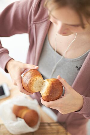 Ein goldbraun ausgebackenes Doppelbrötchen mit glänzender, glatter Oberfläche wird an der Anbackstelle auseinandergebrochen.