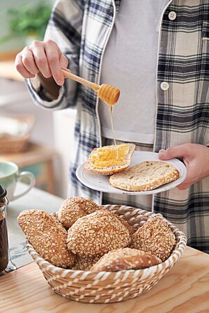 Auf ein halbiertes Dinkel-Haferbrötchen wird Honig geträufelt. Die goldbraun ausgebackenen, mit Haferflocken bestreuten Crispy Oats haben eine lockere, mittelporige Krume.